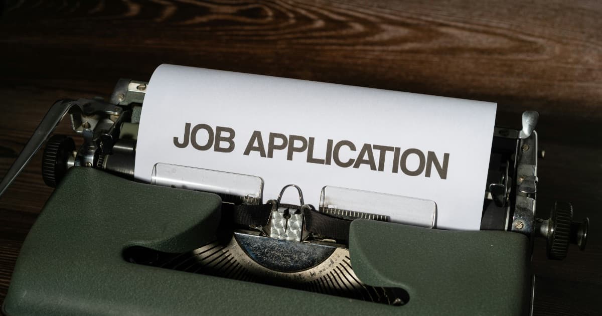 A sheet of paper headed JOB APPLICATION rolled into a vintage typewriter